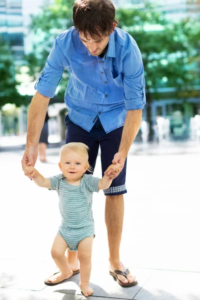 Bambino che fa i primi passi con l'aiuto dei padri — Foto Stock