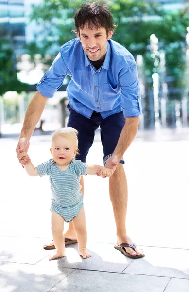 Bebé dando los primeros pasos con los padres ayudan — Foto de Stock