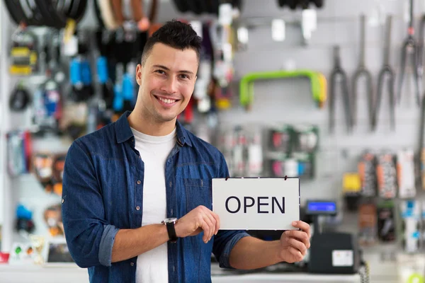 Hombre sosteniendo letrero abierto en tienda de bicicletas —  Fotos de Stock