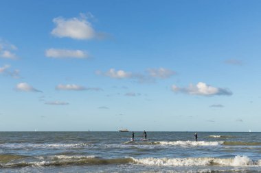 Koksijde, Belçika - 4 Kasım 2020: İnsanlar Kuzey Denizi 'nden geçen bir balıkçı teknesini izliyor