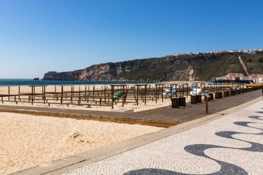 Nazare, Portekiz - 28 Haziran 2021: Arka planda deniz feneri olan Nazare plajı manzarası 