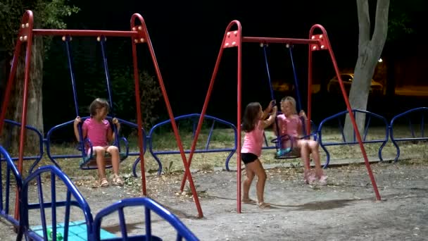 Három Lány Játszótéren Élvezi Éjszakát Szabadban Lányok Hintáznak Szabadban Éjjel — Stock videók