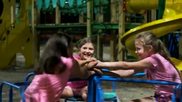 快乐的孩子们晚上在公园里骑着孩子们的旋转木马 三个女孩和一个男孩在游乐场玩乐 — 图库视频影像