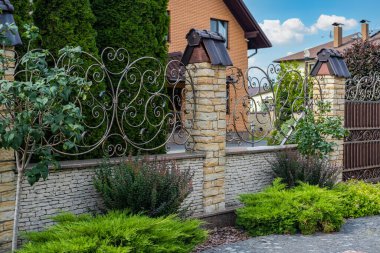 Konut binasının önündeki dekoratif tuğla sütunlar arasında demir işlemeli çit..