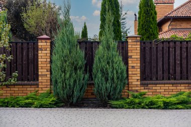 Güzel dekoratif, modern, tuğla kolonları olan ahşap çitler..