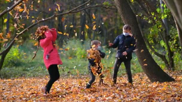 Małe Dzieci Maskach Medycznych Rzucają Spadającymi Żółtymi Liśćmi Parku Jesienią — Wideo stockowe