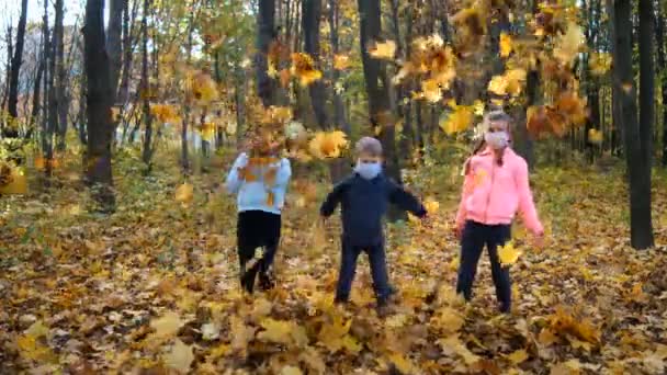 Bambini Piccoli Con Maschere Mediche Lanciano Foglie Gialle Cadute Nel — Video Stock