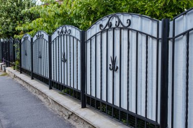 Gri kıvrımlı demir parmaklıklara dövülmüş metal parmaklıklar..