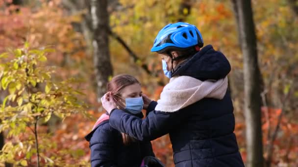 Mamá Pone Una Máscara Médica Casco Bicicleta Para Hija Otoño — Vídeos de Stock
