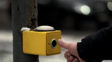 Bir kış akşamı yaya geçidi için trafik ışığını yakmak için düğme. Yakın plan. Bir el yaya geçidinde trafik ışığı düğmesine basar.