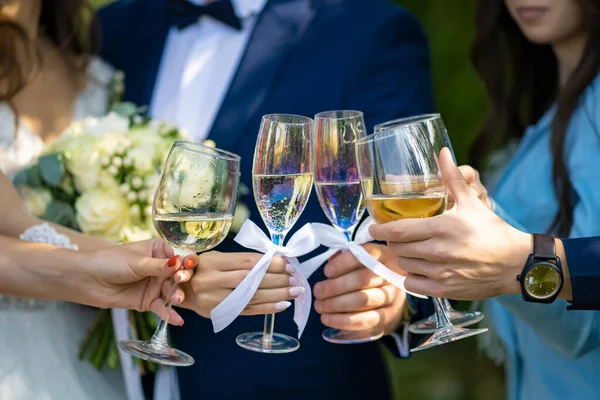 A noiva, o noivo e os hóspedes mantêm copos de champanhe de perto na natureza. — Fotografia de Stock