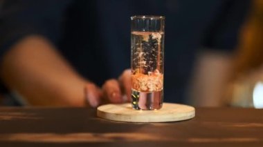 Barmen bardağı hazır bir içecekle ileri itiyor: Sambuca 'daki Baileyler. Gece kulübünde özel içkilerin hazırlığı..