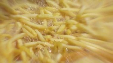 Patates kızartması büyük bir tencerede kızartılır. Kapat. Yağda kızartılmış patates. 4k video merkeze odaklanmış ve kenarları bulanıklaştırılmış.
