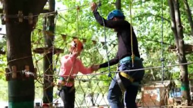 Rope park. A little girl with an instructor overcomes obstacles suspended steps. Sports recreation and entertainment.