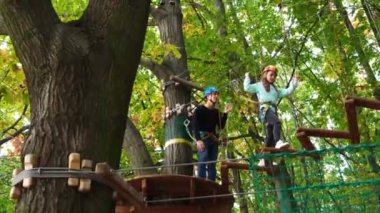 Rope park. A little girl with an instructor overcomes obstacles suspended steps. Sports recreation and entertainment.
