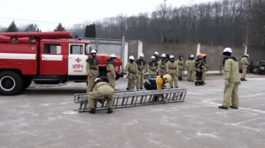 Ukraine, Vinnytsia, circa 2021. Training of young rescuers and firefighters at the training ground. Firefighters run with an assault ladder to the training tower.