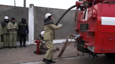 Ukraine, Vinnytsia, circa 2021. Training of young rescuers and firefighters at the training ground. Firefighters install hydrants and connect the hose to the car.