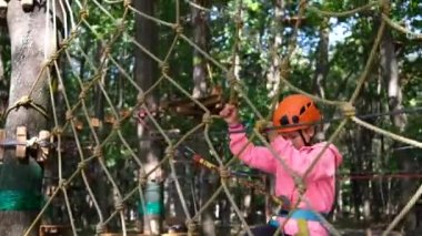 İp parkı. Küçük kız ağ ağının engellerinin üstesinden geliyor. Spor eğlencesi..