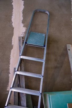 Boyanmamış bir duvarın arkasında metal bir merdiven var..