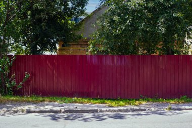 Bir yerleşim yerinin önündeki kırmızı metal çitle çevrili. Profilli metalin dokusu.