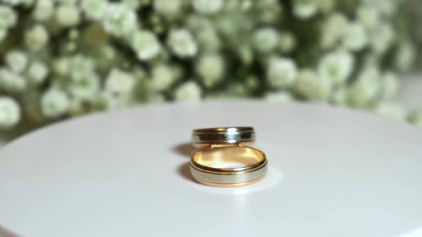 결혼식 부케를 배경으로 아름다운 결혼반지들 회전한다 — 비디오