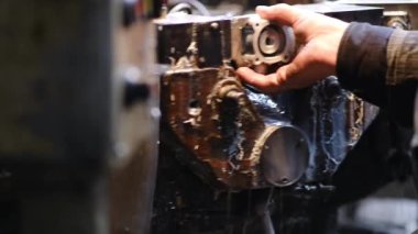 Araba ve traktörler için yedek parça üretimi fabrikası. Toplu makine aracı. İşçi işlem için alüminyum bir bölme yerleştirir. Yakın plan..