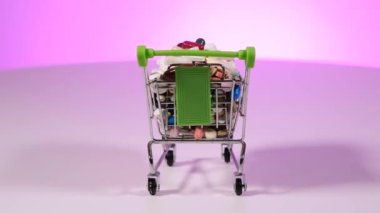 Yeşil saplı metal dekoratif küçük alışveriş arabası beyaz arka planda dönüyor. Tabletlerle dolu olmak. Arabada bir sürü hap var. .