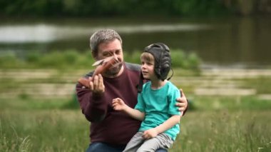 Sakallı bir baba ve oğlu doğada tahta bir oyuncak uçakla oynuyorlar. Bir adam bir çocuğa pilot kaskı takıyor. Geçmişten anılar.
