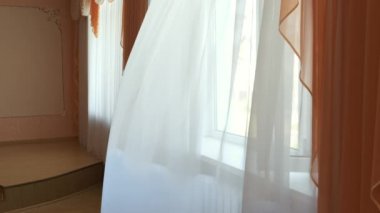 Pencerede şeffaf bir perde var, rüzgarla hafifçe hareket ediyor. Güneş ışığı. Güneş ışınları şeffaf tüllerin içinden parlıyor.