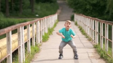 Küçük bir çocuk eski demir bir köprüde hip hop yapıyor..