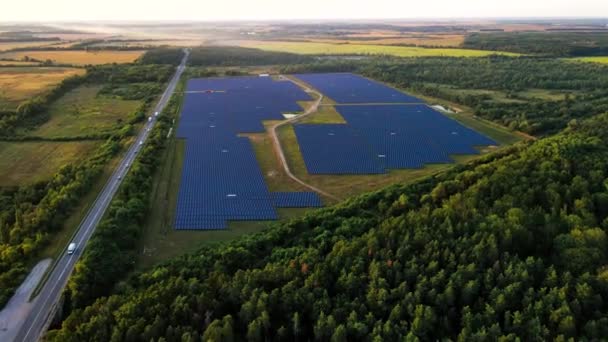 Painéis solares nas linhas no campo perto da estrada. uma visão de pássaros-olho de cima. Energia solar, painéis solares, conceito de fazenda solar. — Vídeo de Stock