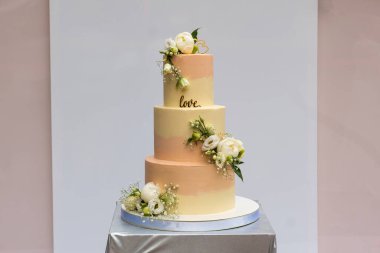 Güzel sarı-pembe bir düğün pastası ve masada canlı güller. .