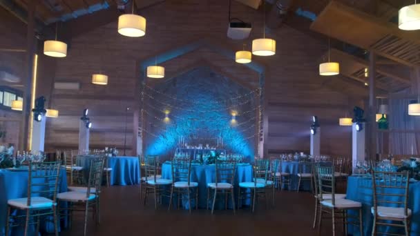 Um elegante salão de banquetes, decorado em estilo azul para uma cerimônia de casamento e iluminado com luz azul em um restaurante acolhedor. movimento da câmera. — Vídeo de Stock