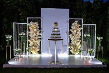 Beyaz ve altın süslemelerle çevrili bir masada düğün pastası.