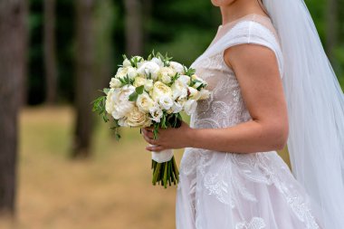Elinde bir buket beyaz çiçek tutan bir gelin.