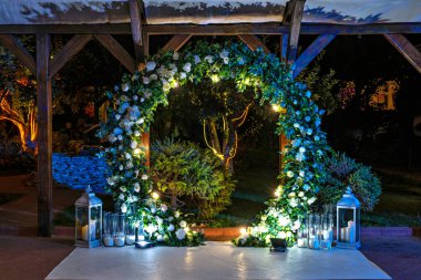 Beyaz çiçekler ve mavi ışıklarla süslenmiş güzel bir kemer yolu