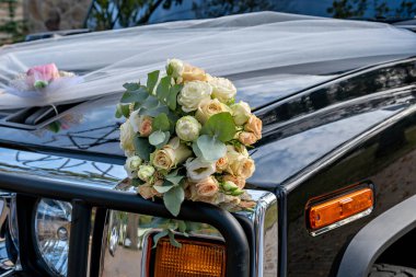 Siyah bir arabanın kaputuna bir buket çiçek konur.