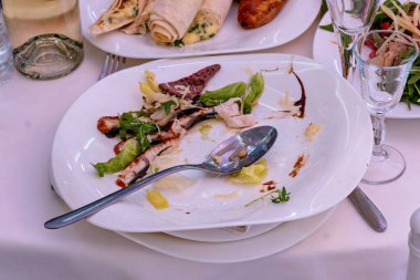 Üzerinde kaşık olan bir tabak yemek diğer tabaklar ve bardaklarla birlikte masada oturuyor.
