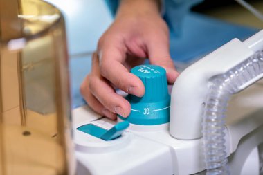 Bir el, üzerinde harfler olan mavi bir düğmeyi ayarlıyor.