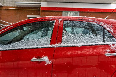 Karla kaplı kırmızı bir araba.
