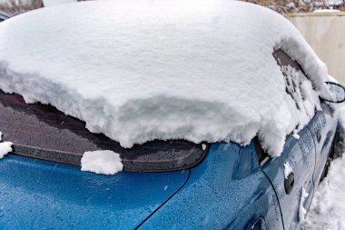 Karla kaplı mavi bir araba.