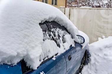 Karla kaplı mavi bir araba.