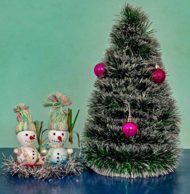 Yanında iki kardan adam olan küçük gümüş bir süs ağacı.