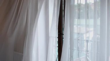 Beyaz perdeli ve balkon manzaralı bir pencere.