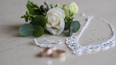 Bir buket beyaz gül ve masada iki alyans.