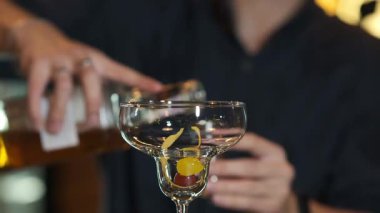 Bir barmen martini bardağına içki dolduruyor.