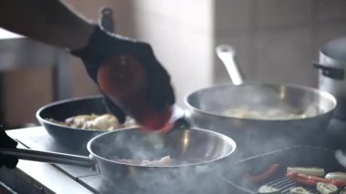 Mutfakta tencere tavayla yemek pişiren bir insan.