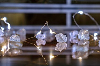 Cam bir yüzeyden yansıyan kristal benzeri ampullerle bir dizi ışığın yakın plan fotoğrafı.