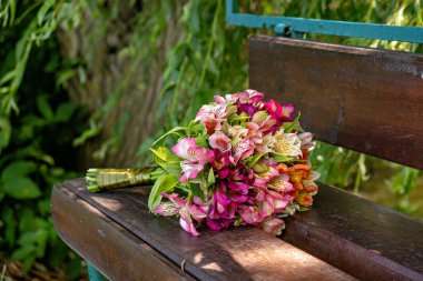 Tahta bir bankın üzerine bir buket çiçek konur.