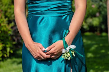 Kolunda yaka çiçeği olan yeşil elbiseli bir kadının yakın çekimi..